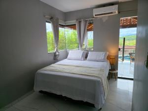 a bedroom with a bed and a large window at Casa Parque do Ribeirão - Casa com piscina in Lençóis +47 photos