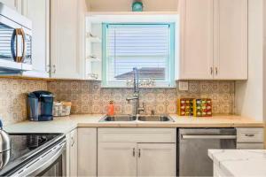 a kitchen with white cabinets and a sink and a window at 4BR Near the BeachFire PitFamily Friendly Stay in Bolivar Peninsula