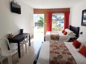 a hotel room with two beds and a desk and a table at Hotel & Resort Villa del Sol in Tumaco
