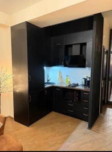 a kitchen with black cabinets and a sink at Cozy Corner in Tbilisi City