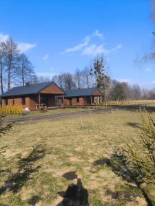 a log cabin with a field in front of it at Azyl na Polesiu domki przy Poleskim Parku Narodowym in Załucze Nowe