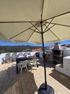 a large umbrella on a patio with tables and chairs at Sol da Praia in Odeceixe