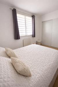 a bedroom with a large white bed with two pillows at Appartement charmant au cœur de Saint-Rémy, idéal pour une escapade provençale ! in Saint-Rémy-de-Provence