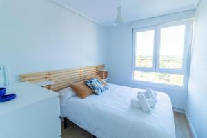 a white bedroom with two beds and a window at Bahía Dorada Loredo - 3 hab, Terraza y Vistas al Mar in Loredo +13 photos