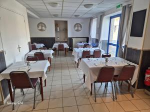 a dining room with white tables and chairs and a tv at Les 4 nuances in Youx
