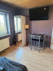 a living room with a table and a television on the wall at Auerandstudio in Nienhagen