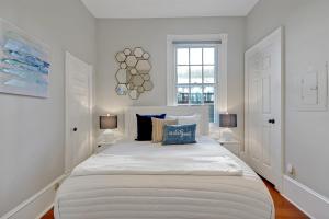 a white bedroom with a large bed with two lamps at Savannah Suite on Front in Wilmington