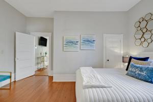a white bedroom with a bed and a tv at Savannah Suite on Front in Wilmington