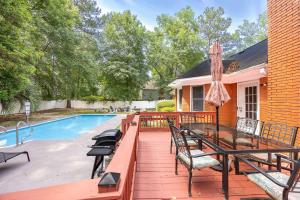 a deck with a table and chairs next to a swimming pool at Market District Pool House in Statesboro