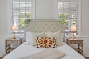 a white bed with a pillow on it with windows at Downtown Bliss in Wilmington