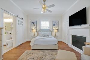 a white bedroom with a bed and a flat screen tv at Downtown Bliss in Wilmington