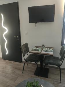 a dining room with a table and two chairs and a television at Chez Olga studio indépendant in Giberville
