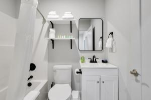 a white bathroom with a sink and a mirror at The Pearl Stylish Couples Getaway in Wilmington