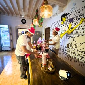 two men wearing santa hats preparing food at a counter at GoSolo Stays Bandra Hostel in Mumbai +70 photos