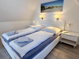 a bedroom with a white bed with two night stands at Haus Meereswoge, Duhnen in Cuxhaven