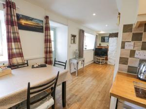 a kitchen and living room with a table and chairs at Happy Landing in Harlech