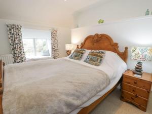 a bedroom with a large bed with a wooden headboard at Happy Landing in Harlech