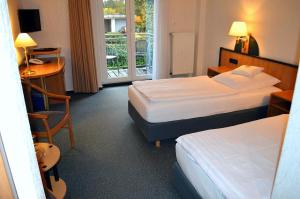 a hotel room with two beds and a desk and a window at Hotel Zur Mühle in Lengerich