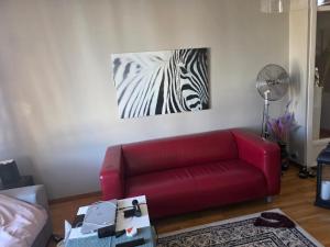 a living room with a red couch and a zebra painting at Ett mysigt appartement in Linköping
