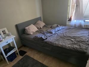 an unmade bed in a small bedroom with a table at Ett mysigt appartement in Linköping