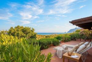 a patio with two chairs and a table and the ocean at Costa Corallina Villa with direct beach access and stunning views in Costa Corallina