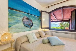 a bedroom with a bed with a painting of a boat at Costa Corallina Villa with direct beach access and stunning views in Costa Corallina