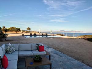 a couch sitting on a patio next to the ocean at My Way Kavos Villa in Agia Marina Aegina