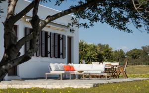 a white couch and tables in front of a house at My Way Kavos Villa in Agia Marina Aegina