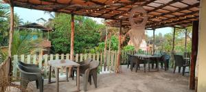 a patio with tables and chairs under a wooden pergola at 4 Bedroom House, Morjim Main Road in Morjim
