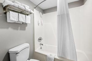a bathroom with a toilet and a shower with towels at Super 8 by Wyndham Kingsport /I-81 in Kingsport +50 photos