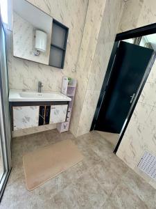 a bathroom with a sink and a black door at Nahé Résidence Deux Plateaux in Abidjan