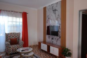 a living room with a chair and a television at Kristina Gardens 1BD & Studio Homes in Voi