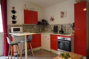 a small kitchen with red cabinets and a table at Maison individuelle in Triac-Lautrait