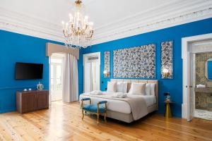 a blue bedroom with a bed and a chandelier at Água Hotels Lagos Bay in Lagos