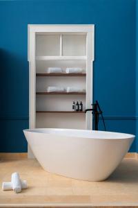 a white bath tub in a bathroom with a blue wall at Água Hotels Lagos Bay in Lagos +38 photos