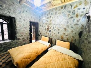two beds in a room with a stone wall at riad imlil in Imlil