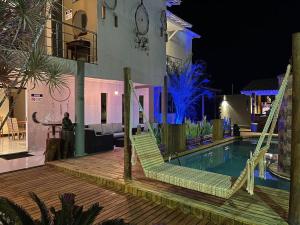 a resort with a swimming pool with chairs and a house at Pousada Macdonald in Eunápolis