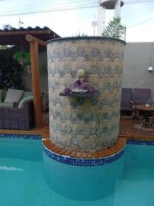 a statue of a woman sitting on a ledge next to a pool at Pousada Macdonald in Eunápolis