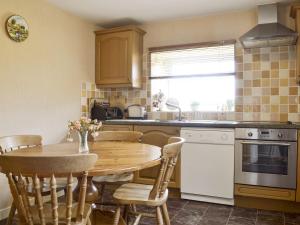 a kitchen with a wooden table and a table and chairs at Bodwi Isaf in Abersoch