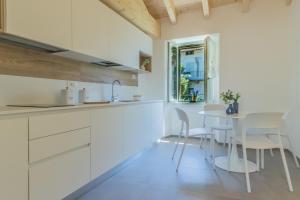 a kitchen with white cabinets and a table and chairs at Ca Magnolia Appartamento 3 in Lierna +20 photos