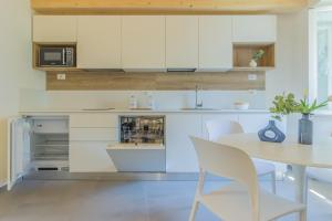 a kitchen with white cabinets and a table and chairs at Ca Magnolia Appartamento 3 in Lierna