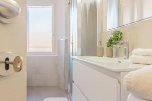a white bathroom with a sink and a mirror at Ca Magnolia Appartamento 3 in Lierna