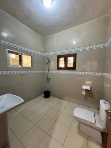 a bathroom with a toilet and a sink and two windows at Ramaya Auberge Espagnole in Grand-Popo