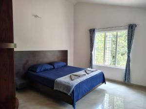 a bedroom with a bed with blue sheets and a window at Sintra Villa in Meppādi