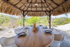 a wooden table and chairs under a straw umbrella at Villa Kas Karibense 38 - Coral Estate in Willibrordus