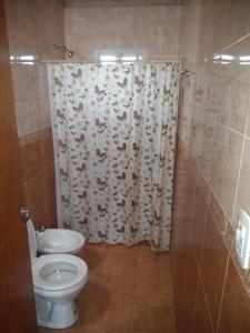 a bathroom with a toilet and a shower curtain at Casa Ibira pita in Pueblo Liebig