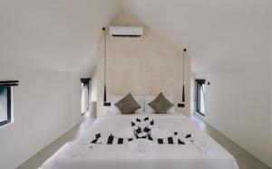 a bedroom with a large white bed with windows at Paniora Loft Villas in Kuta Lombok