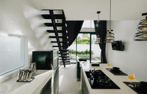 a kitchen with white counters and a spiral staircase at Paniora Loft Villas in Kuta Lombok