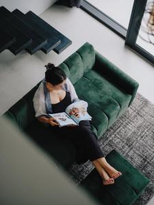 a woman sitting on a couch reading a book at Paniora Loft Villas in Kuta Lombok