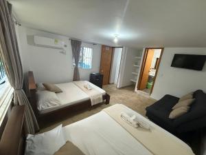 a hotel room with two beds and a couch at Hotel Santorini Doradal in Doradal +3 photos